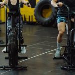Home Two people exercising on stationary bikes at a modern gym.